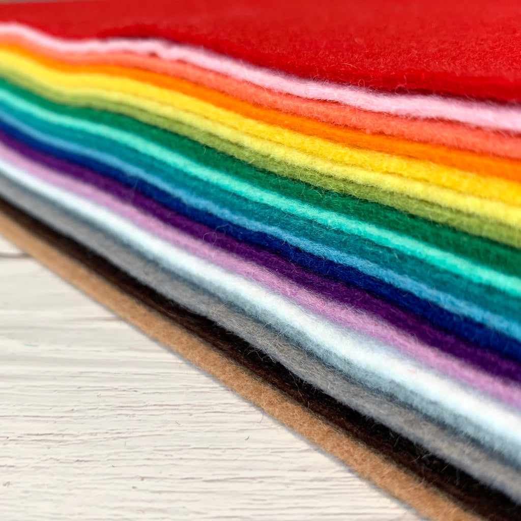 A stack of felt in rainbow order on a white wood surface