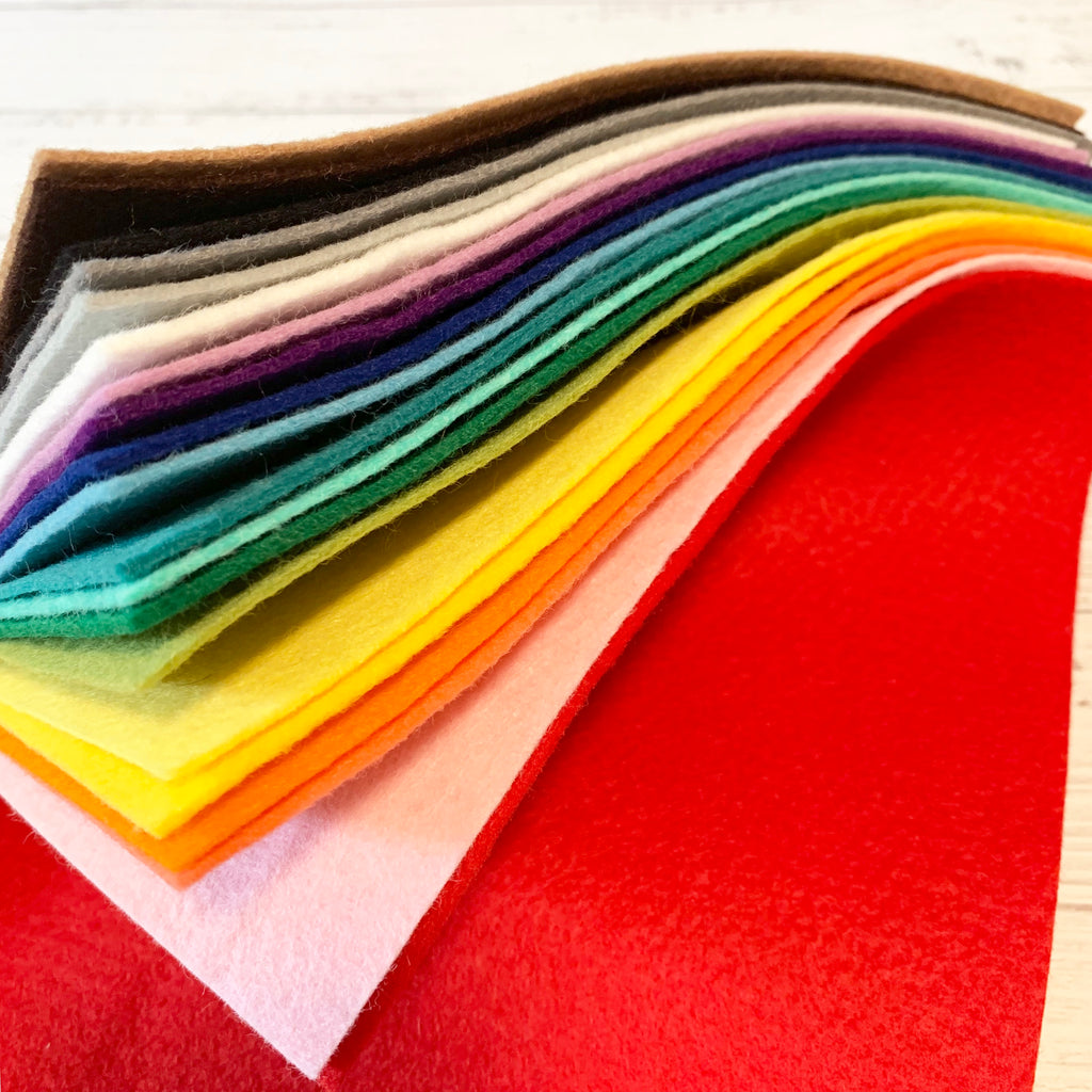 A stack of felt in rainbow order on a white wood surface