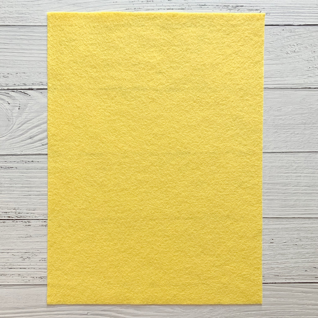 one 8 x 10 sheet of light yellow colored felt on a white wood background