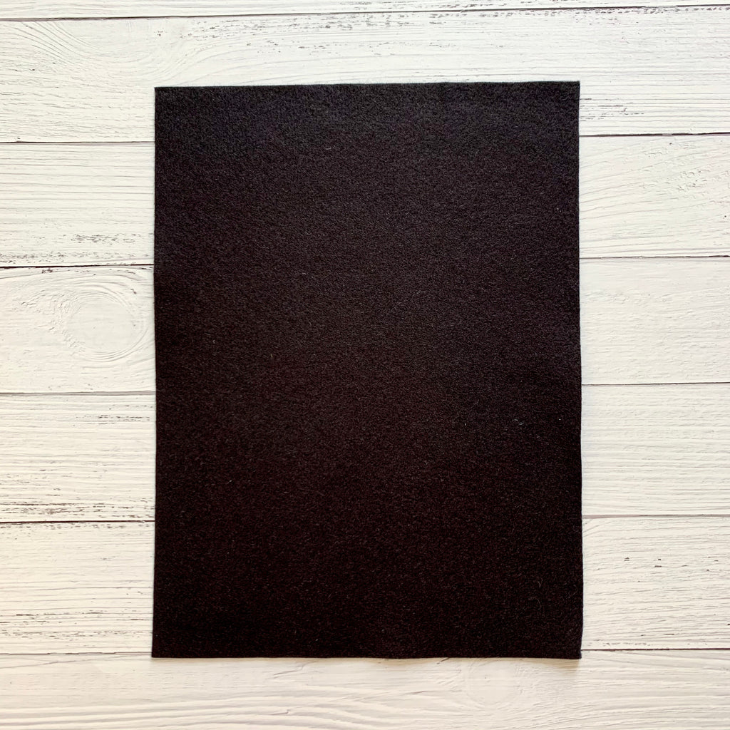 one 8 x 10 sheet of black colored felt on a white wood background