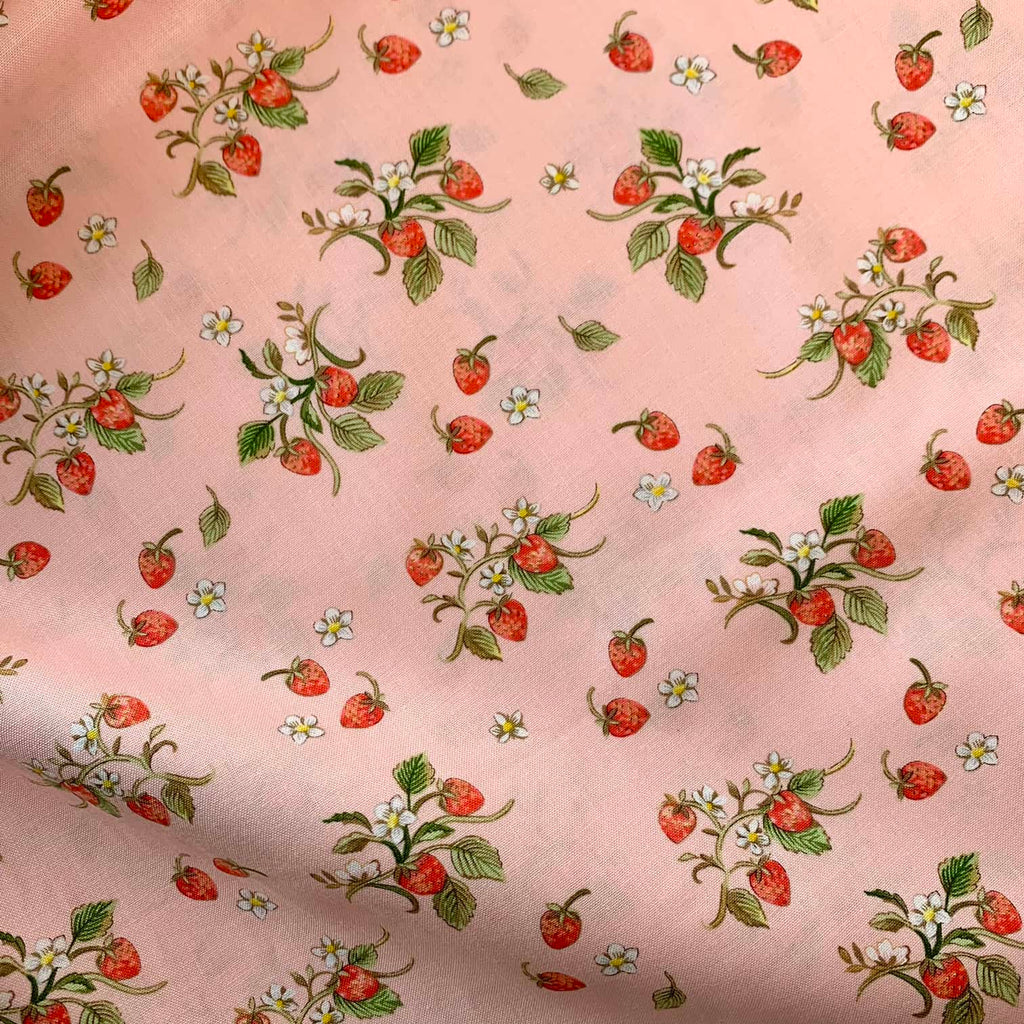 a close up of quilting cotton fabric that features illustrated strawberries repeated over a pink background