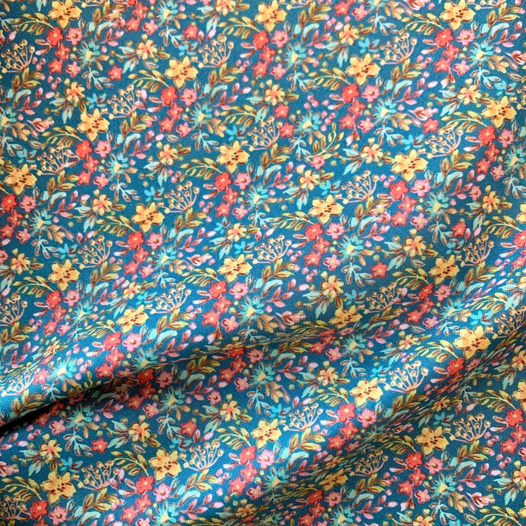 A close up of teal ditsy floral quilting cotton fabric