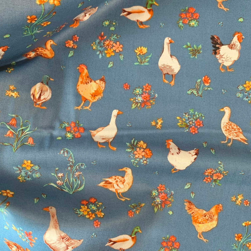 a close up of quilting fabric that features geese, ducks, and chickens repeated over a blue background