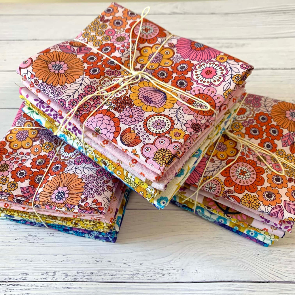 three neatly folded bundles of vintage floral cotton fabrics