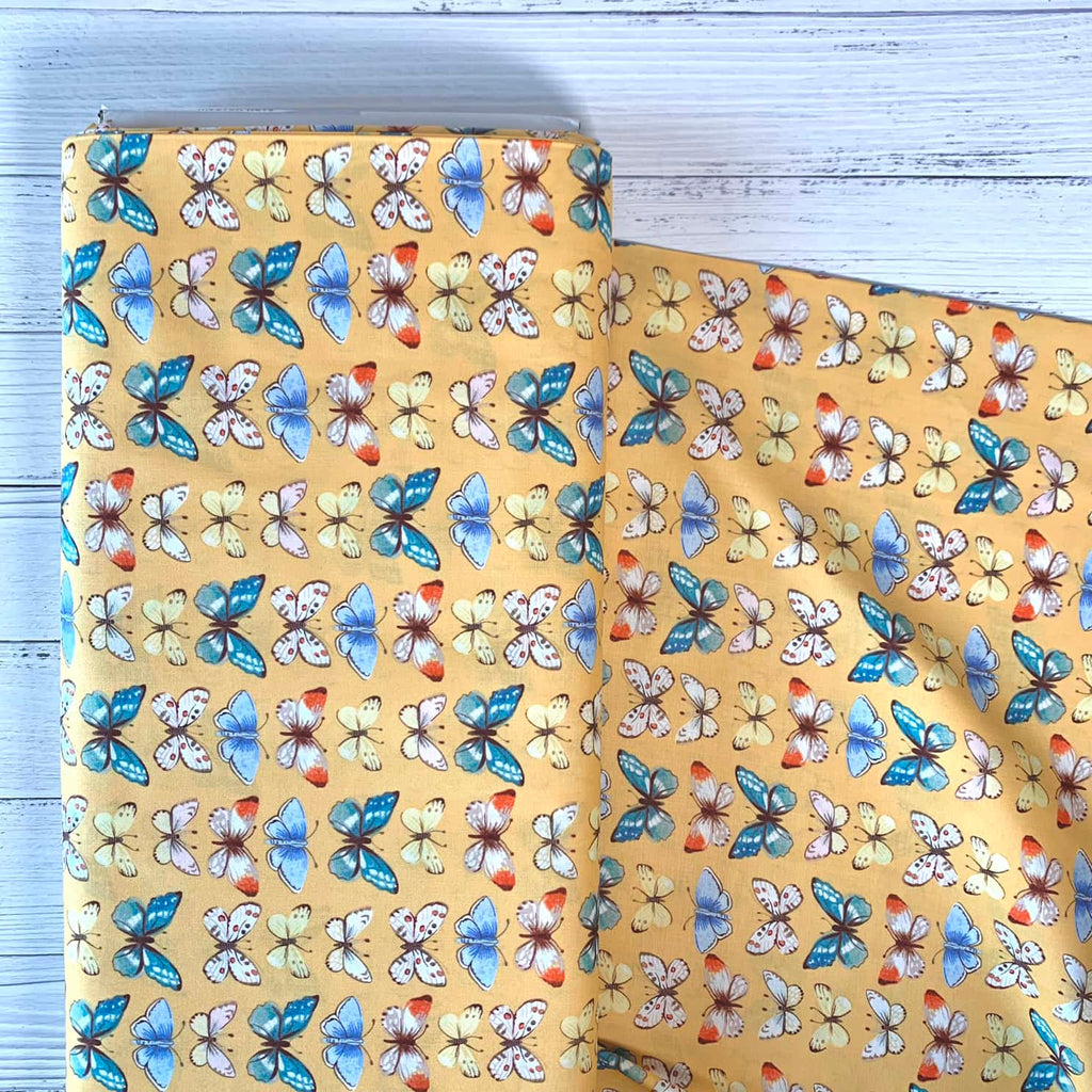 a bolt of quilting fabric that features butterflies repeated over a yellow background